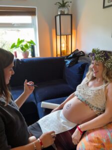 Pregnant woman having her bump painted with henna at her mother blessing celebration